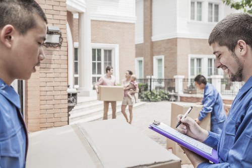 Students moving boxes and furniture in Queens Park on a residential street