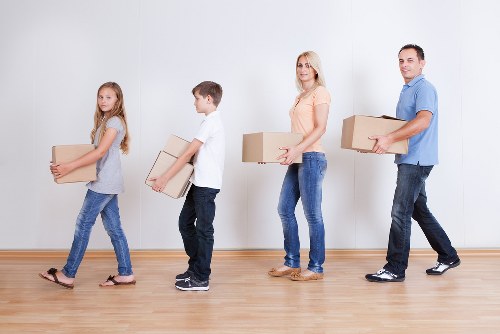 Professional movers carrying furniture down stairs in a Queens Park property